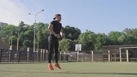 Young man does jump exercises at green playground. Athletic man jumping Video stock 115027036