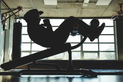 A young man does a press exercise on a special simulator. Silhouette shooting Foto stock