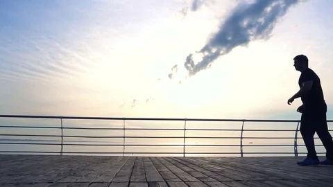 Young man does round house high kicks barefooted against sunrise in slow motion Stock Footage 77726301