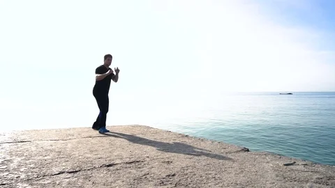 Young man does round house high kicks barefooted against sunrise in slow motion Stock Footage 78112050