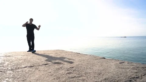 Young man does round house high kicks barefooted against sunrise in slow motion Stock Footage 78112297