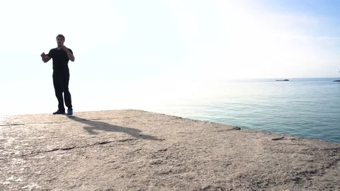 Young man does round house high kicks barefooted against sunrise in slow motion Stock Footage 78142932