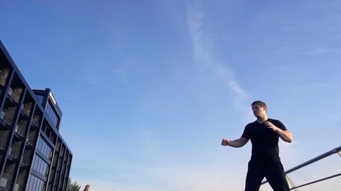 Young man does round house high kicks barefooted against sunrise in slow motion Stock Footage