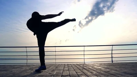 Young man does round house high kicks barefooted against sunrise in slow motion Stock-Footage 79181121