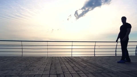 Young man does round house high kicks barefooted against sunrise in slow motion Stock Footage 79181927