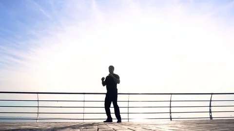 Young man does round house high kicks barefooted against sunrise in slow motion Stock Footage 79184899