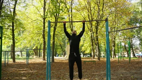 A young man does sports, pulling up on a horizontal bar Stock Footage 233277657