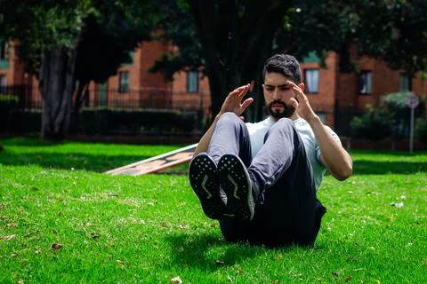 Young man doing abdominal exercise in a park in the city Stock Photos