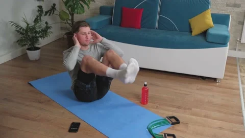 Young man doing abdominal exercises at home on a blue mat. Stock Footage 144109044
