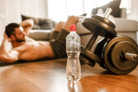 Young man doing abs exercising at home on the couch. Cut view of hardwoking t Stock Photos