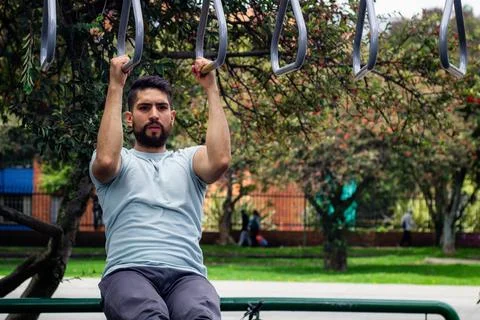 Young man doing arm exercise in a park in the city Stock Photos