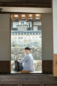 A young man doing a backpacking trip in a Korean traditional house. Stock Photos