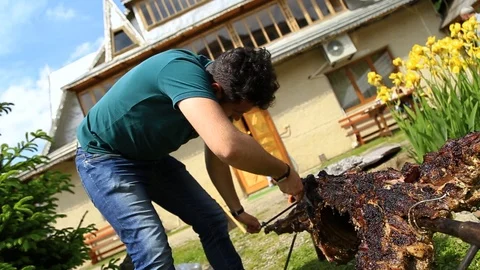 Young man doing bbq and cutting the meat Stock Footage 98984455