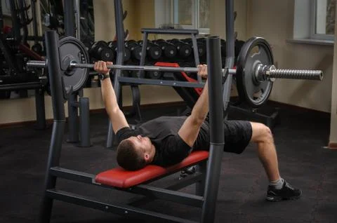 Young man doing bench press workout in gym Stock Photos