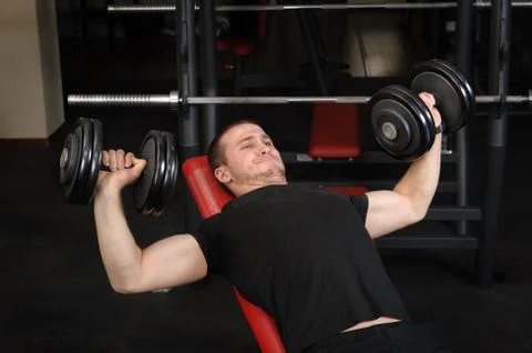 Young man doing bench press workout in gym Stock Photos