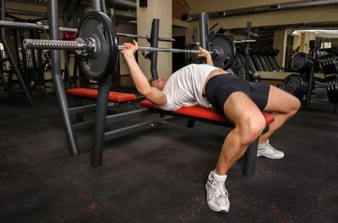 Young man doing bench press workout in gym Stock Photos