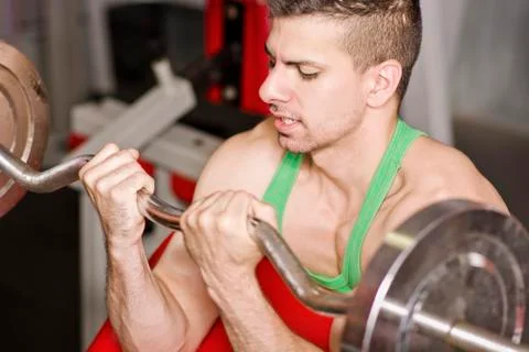 Young man doing biceps bar exercises Stock Photos