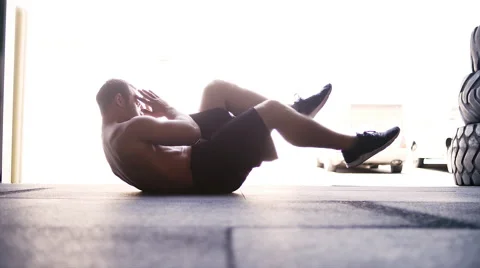A young man doing a bicycle crunch in a small gym Stock Footage 57658052