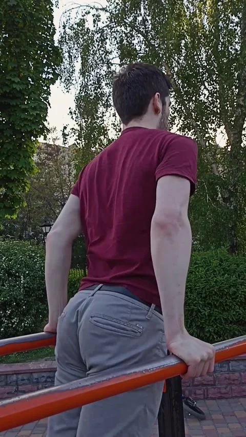 Young man doing dips on parallel bars, viewed from behind Stock Footage 312299268