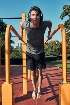 Young man doing dips on parallel bars during his workout in a modern calisthe Stock Photos