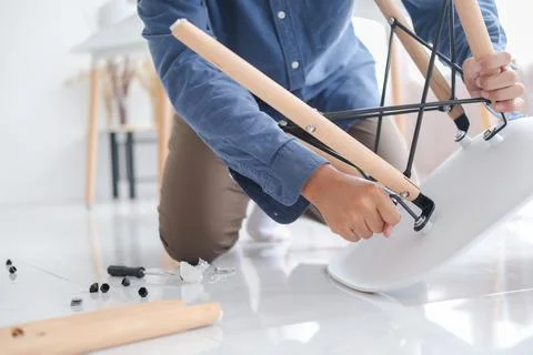 Young man doing DIY work, assembling furniture at home. Stock Photos