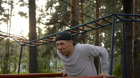 Young man doing exercise at the horizontal bar in the evening Stock Footage 64017696
