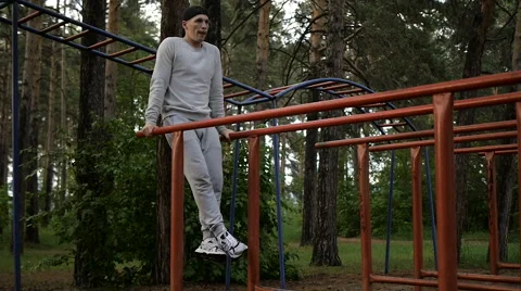 Young man doing exercise at the horizontal bar in the evening 스톡 동영상 64017924