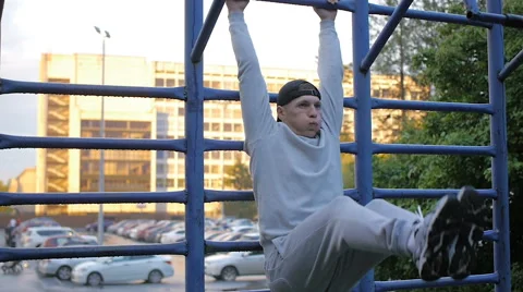 Young man doing exercise at the horizontal bar in the evening Stock Footage 64019003