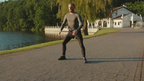 Young man doing exercise near lake at outdoor workout at sunlight sportswear Stock Footage 138641697