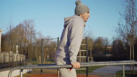 Young man doing exercise on parallel bars outdoors Stock Footage 129555475