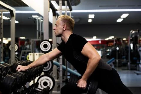 Young man doing the exercises with dumbbell at biceps for good body in fitnes Stock Photos