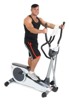Young man doing exercises on elliptical cross trainer Stock Photos