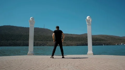 A young man doing exercises in the morning on the embankment of a large lake Stock Footage 105970331