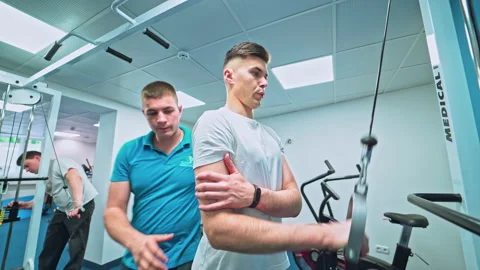 Young man doing exercises under physiotherapist supervision Stock Footage 132029647