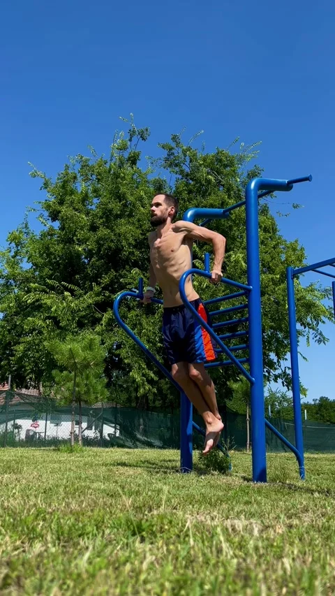 Young man doing exercises on the uneven bars on the sports ground in open air Stock Footage 248531641