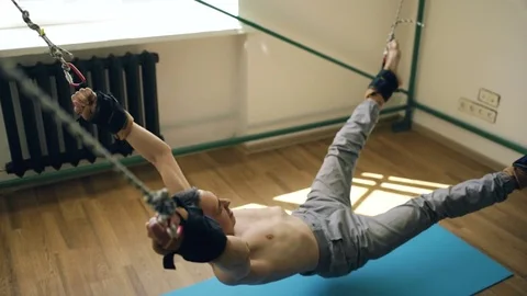 Young man doing exircise on quartering fitness equipment and pull his arms and Stock Footage 75647290