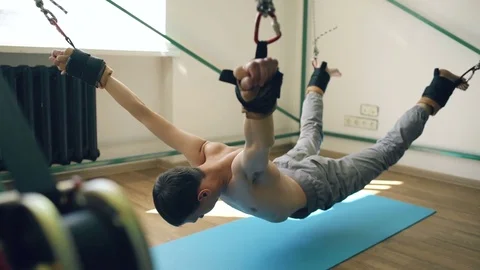 Young man doing exircise on quartering crossfit equipment and pull his arms and Stock Footage 75647755
