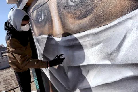 A young man is doing a graffiti inspired by the measures against coronavirus Stock Photos