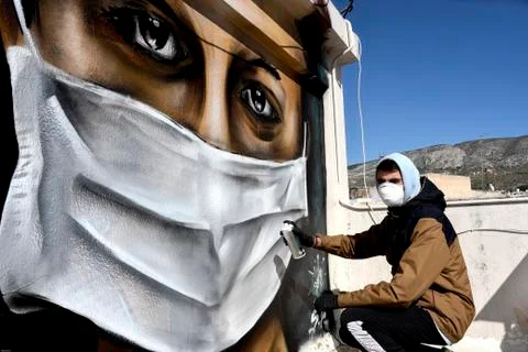 A young man is doing a graffiti inspired by the measures against coronavirus Stock-Fotos
