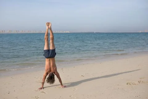 Young man doing handstand on the beach. Foto stock