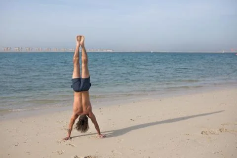Young man doing handstand on the beach. Stock-Fotos