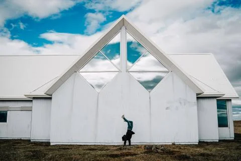Young man doing a handstand in front of traditional wooden white house and bl Foto stock