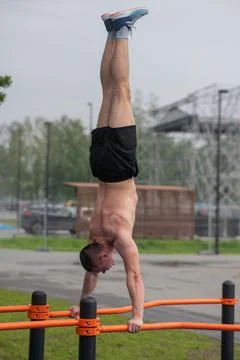 A young man doing a handstand on parallel bars outdoors. Workout. Foto stock