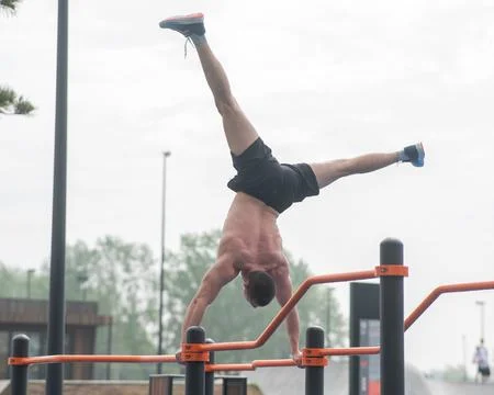 A young man doing a handstand on parallel bars outdoors. Workout. Foto stock