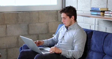 Young man doing home work with his laptop Stock Footage 136065353