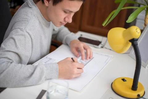 Young man doing homework by drawing using a ruler a t-square Stock Photos