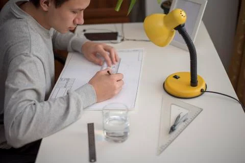 Young man doing homework by drawing using a ruler a t-square Stock Photos
