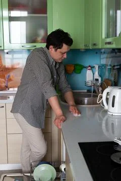 Young man doing homework in the kitchen. Washing dishes in a dishwasher. Dad  Stock Photos