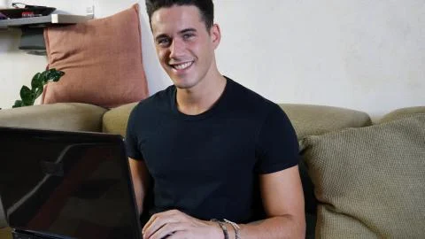 Young Man Doing Homework on Laptop on Couch Stock Photos