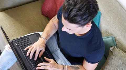 Young Man Doing Homework on Laptop on Couch Stock Photos